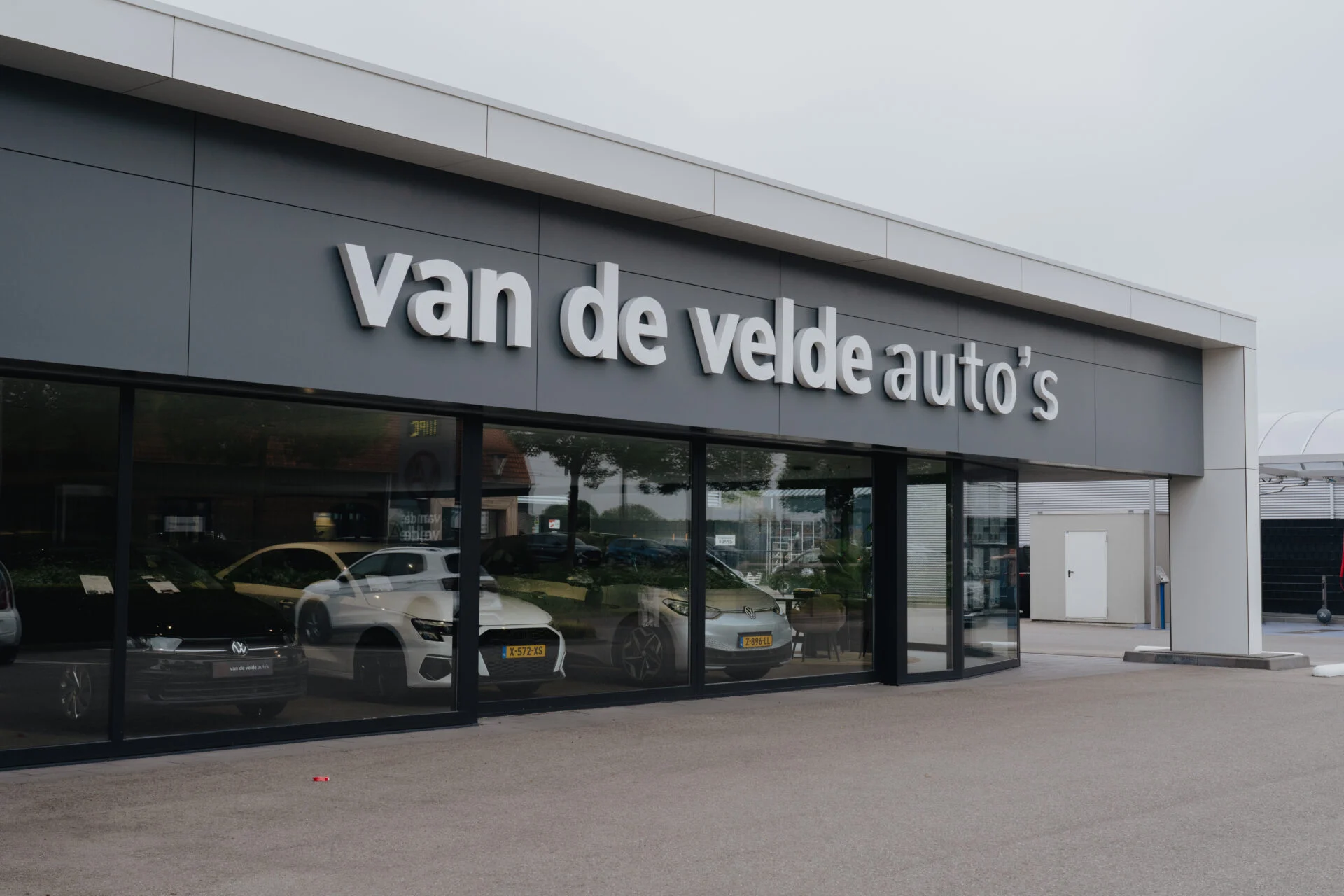 Witte gevelletters van de velde auto's op autoshowroom