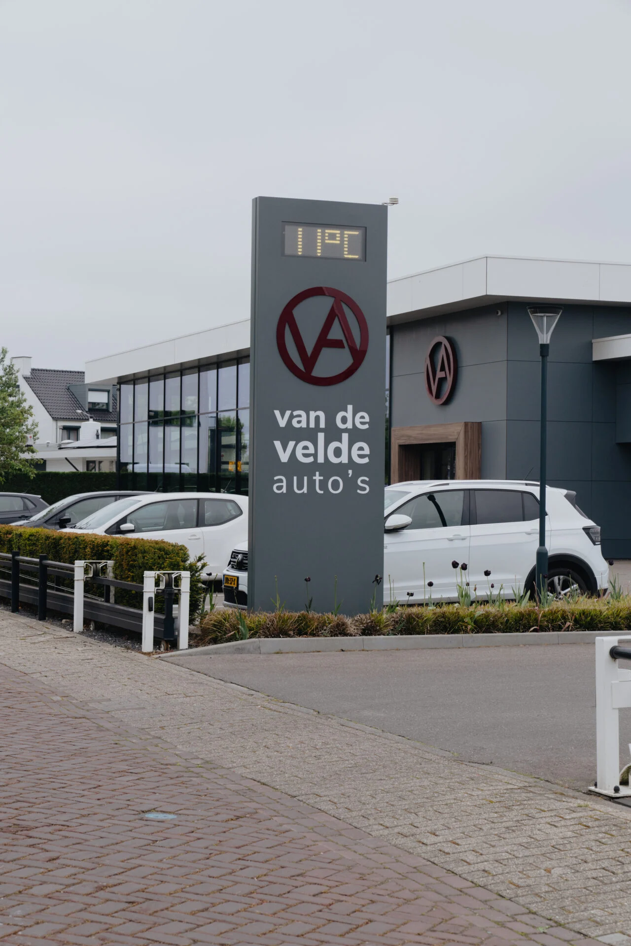 Verlichte reclamezuil met temperatuurdisplay en logo van de velde auto's