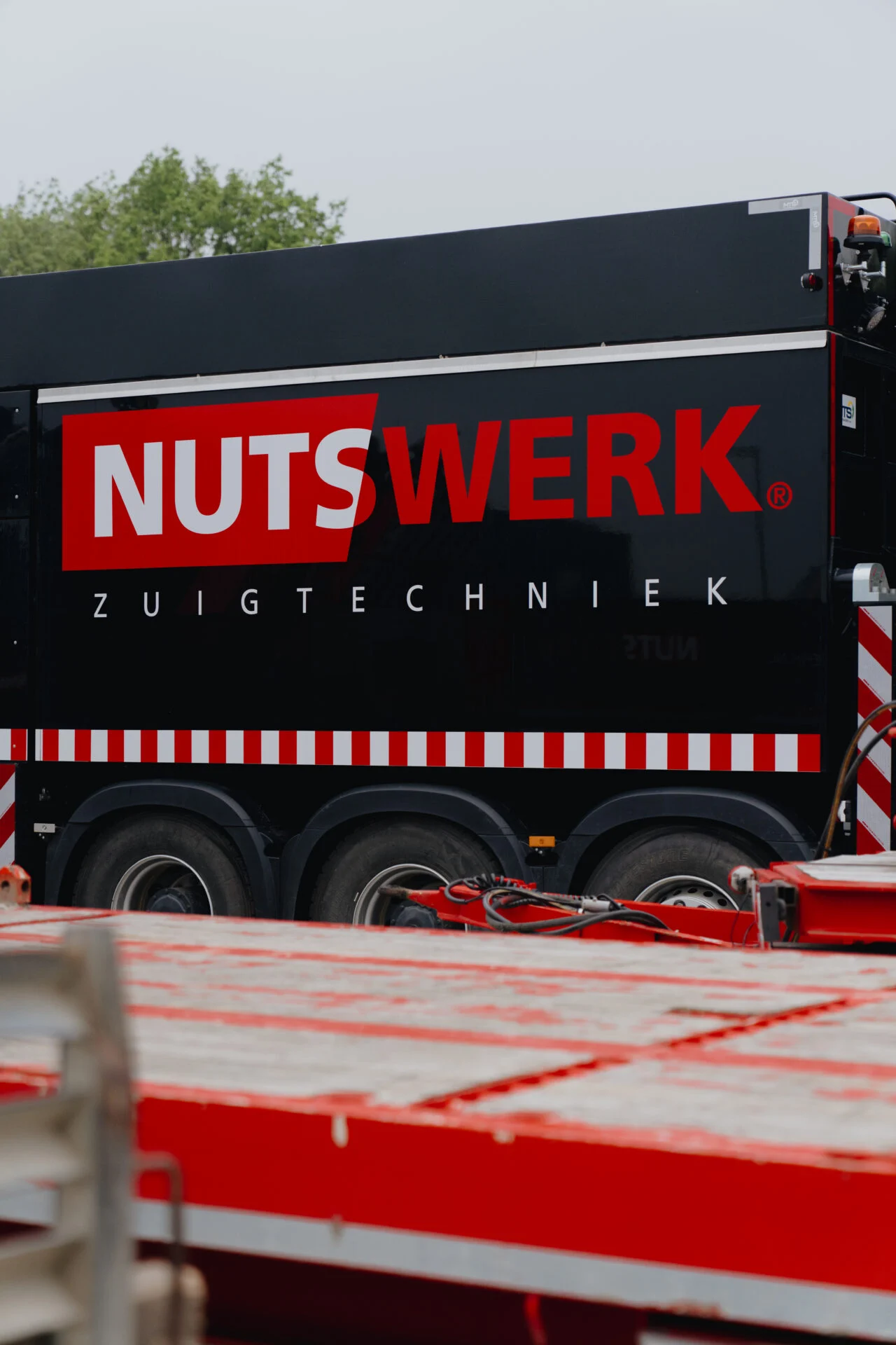 Zijbelettering NUTSWERK Zuigtechniek op zwarte zuigwagen
