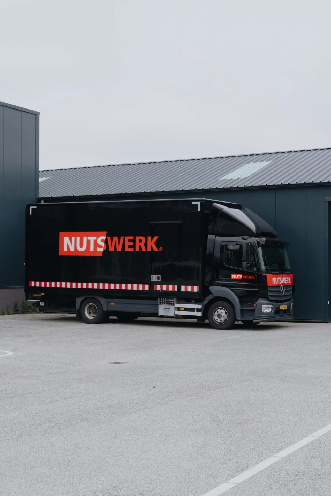 Voertuigbelettering Nutswerk op zwarte vrachtwagen